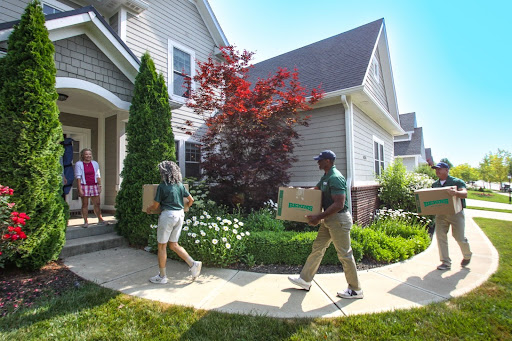 Bekins employees carrying boxes into a house.