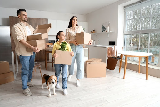 Happy family with boxes and Beagle dog in kitchen on moving day